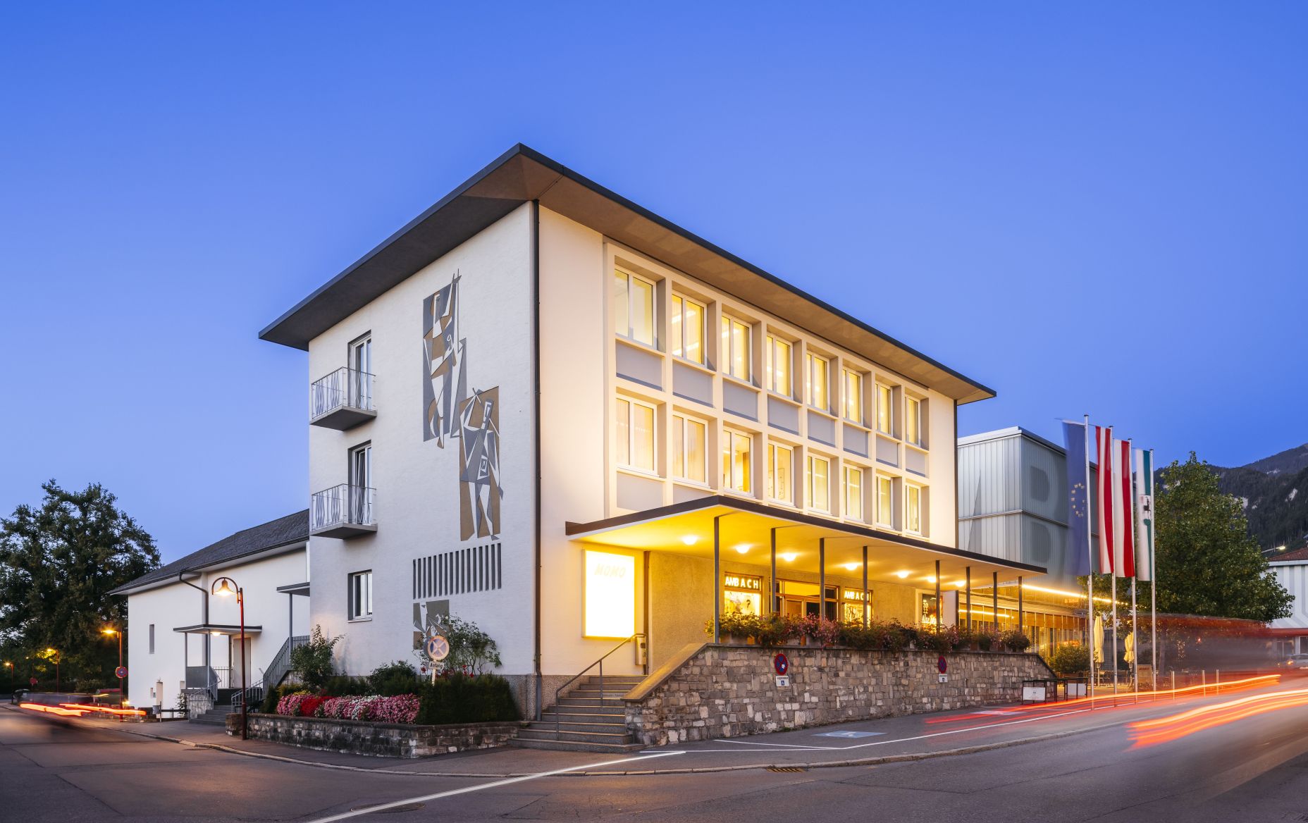 Kulturbühne Ambach in Götzis zur blauen Stunde, Außenansicht mit beleuchtetem Eingang